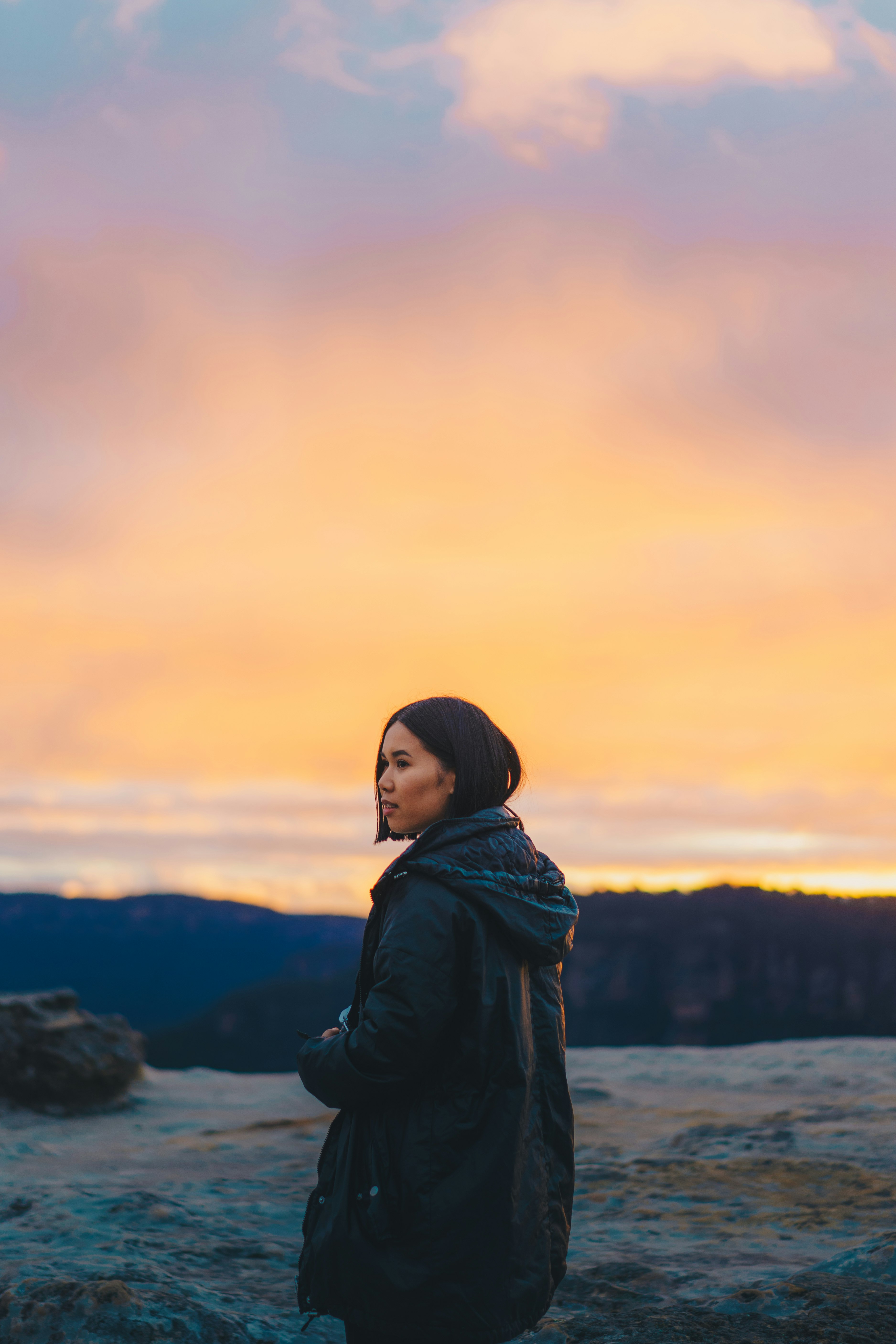 woman in black jacket standing on hill during daytime